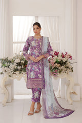 Woman in a purple floral dress with a white dupatta standing in a decorated room with flowers.