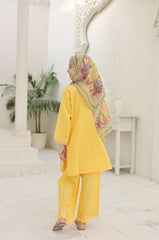 Woman in a yellow outfit with a colorful headscarf in a white interior setting