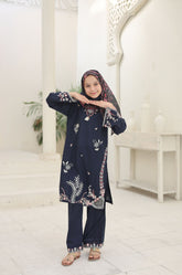 Person wearing a navy blue embroidered outfit in a white room