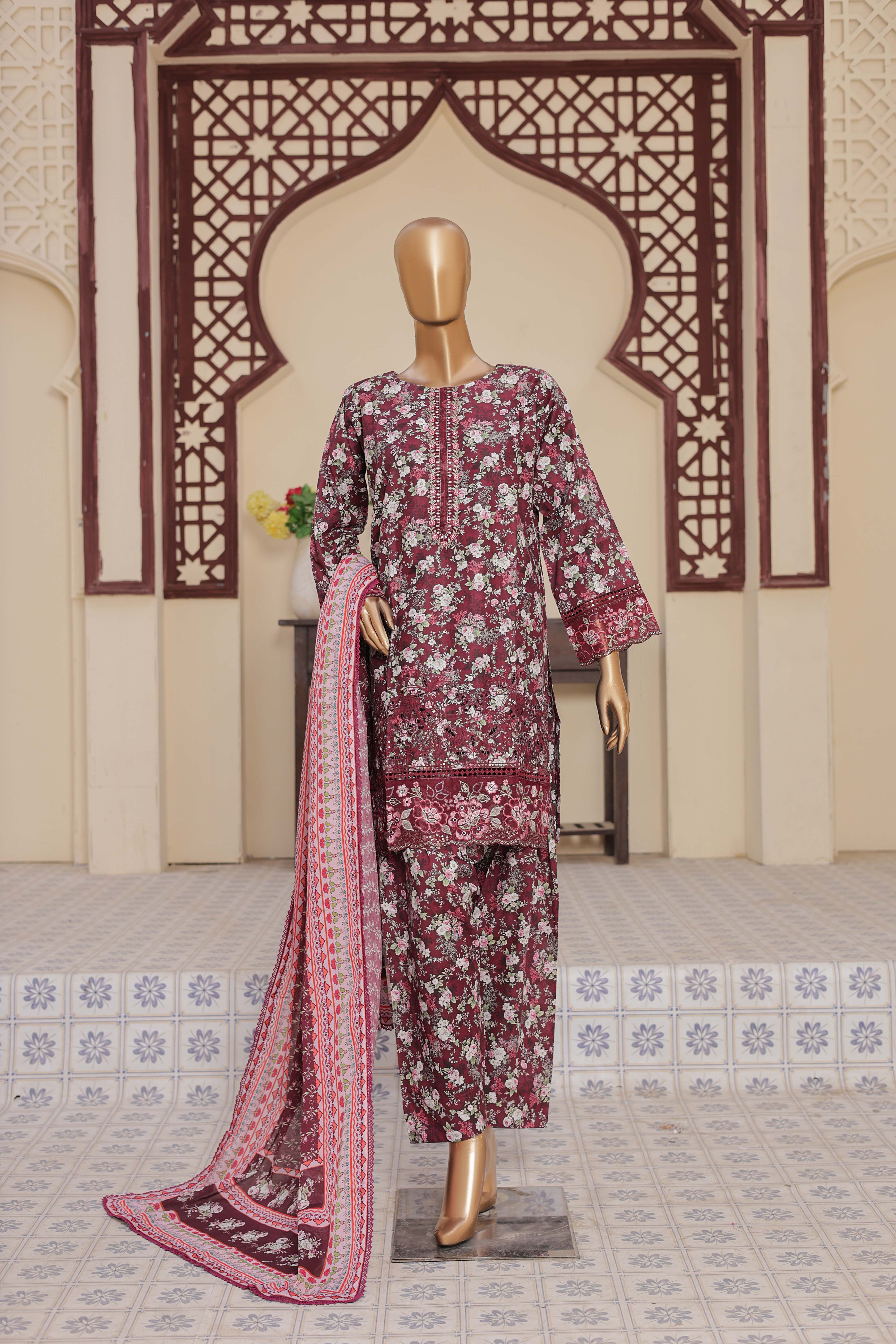 Mannequin wearing a patterned outfit with a long scarf in front of an ornate wall.