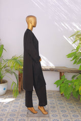 Mannequin wearing a black outfit in a room with plants and a tiled floor.
