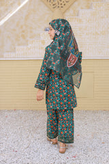 Woman wearing a floral outfit with a matching headscarf in an outdoor setting.