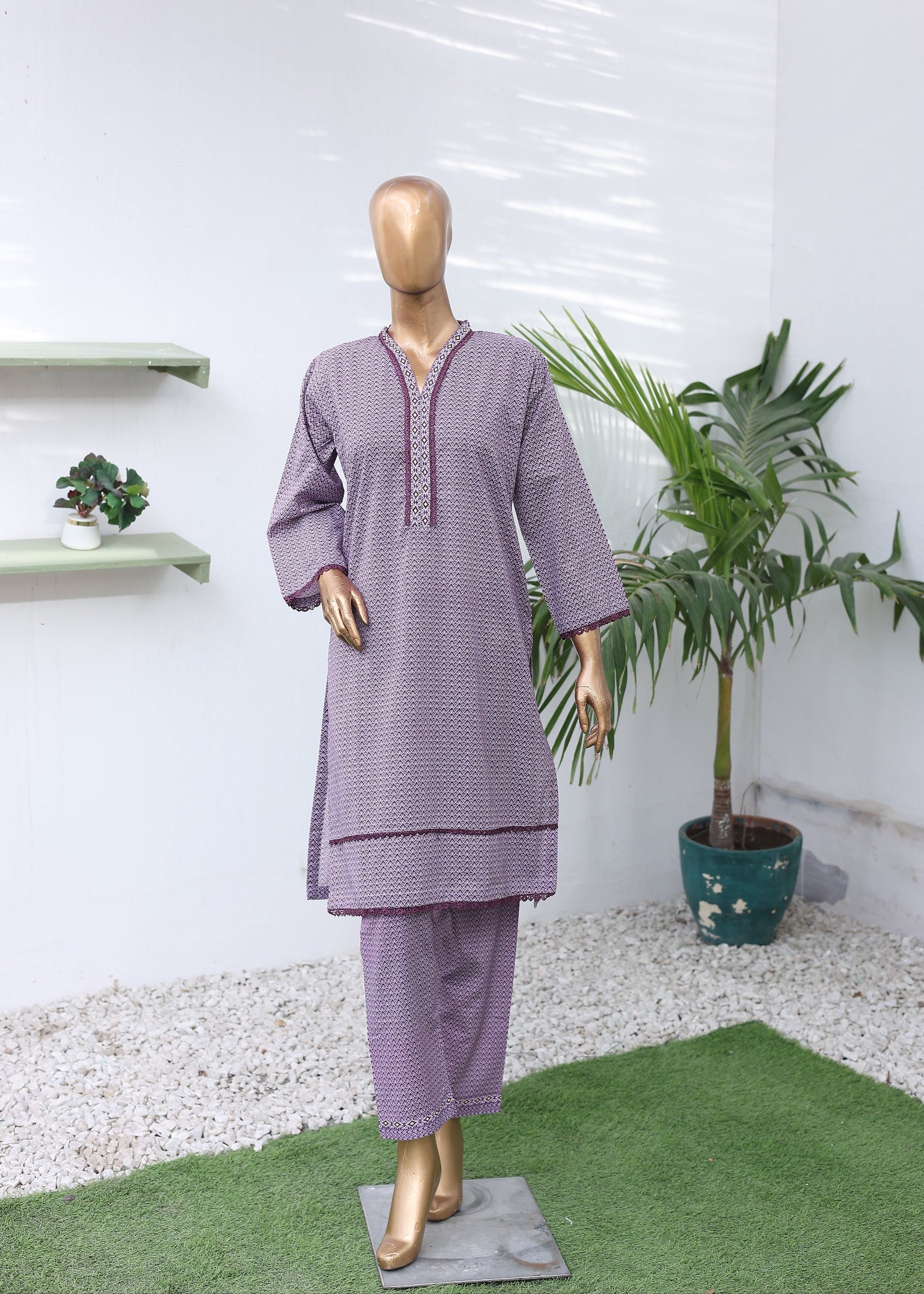 Mannequin wearing a purple outfit with a white background and plant