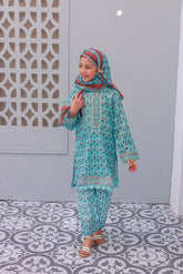A young girl wearing a blue embroidered festive outfit with matching dupatta, posing against a patterned background.