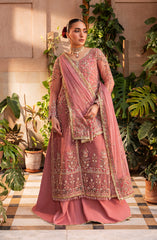 Woman in a traditional pink embroidered outfit standing among plants.