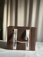 Dark Brown Tote with a white strap featuring 'fineur' branding, placed on a surface with a plant in the background.