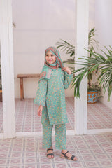 Child wearing a green traditional outfit with a headscarf in a room with white columns and plants.