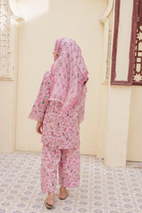 Person wearing a pink floral outfit in a room with decorative tiles and a mirror.