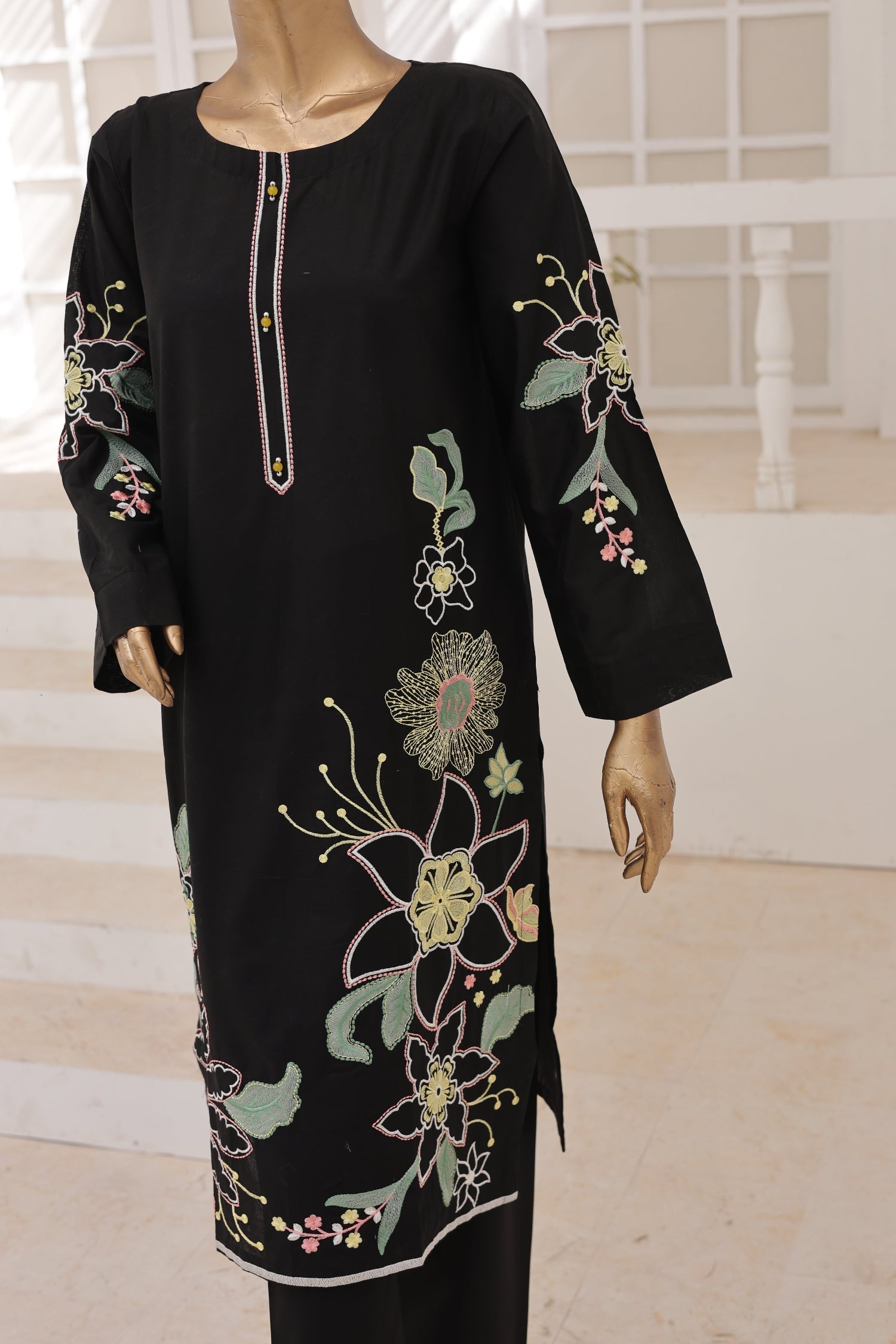 Black dress with floral embroidery on a mannequin against a neutral background