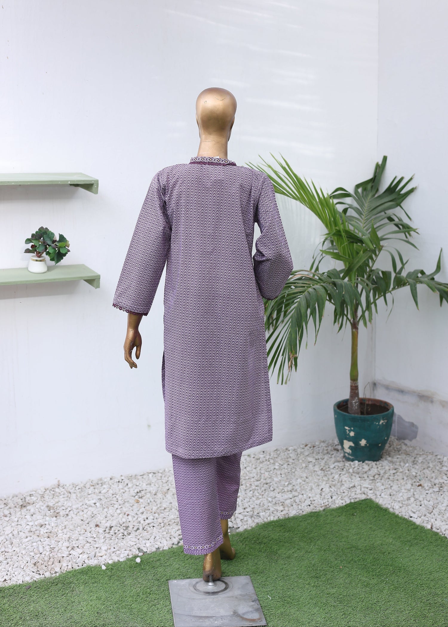 Mannequin wearing a purple outfit with a white background and plants.