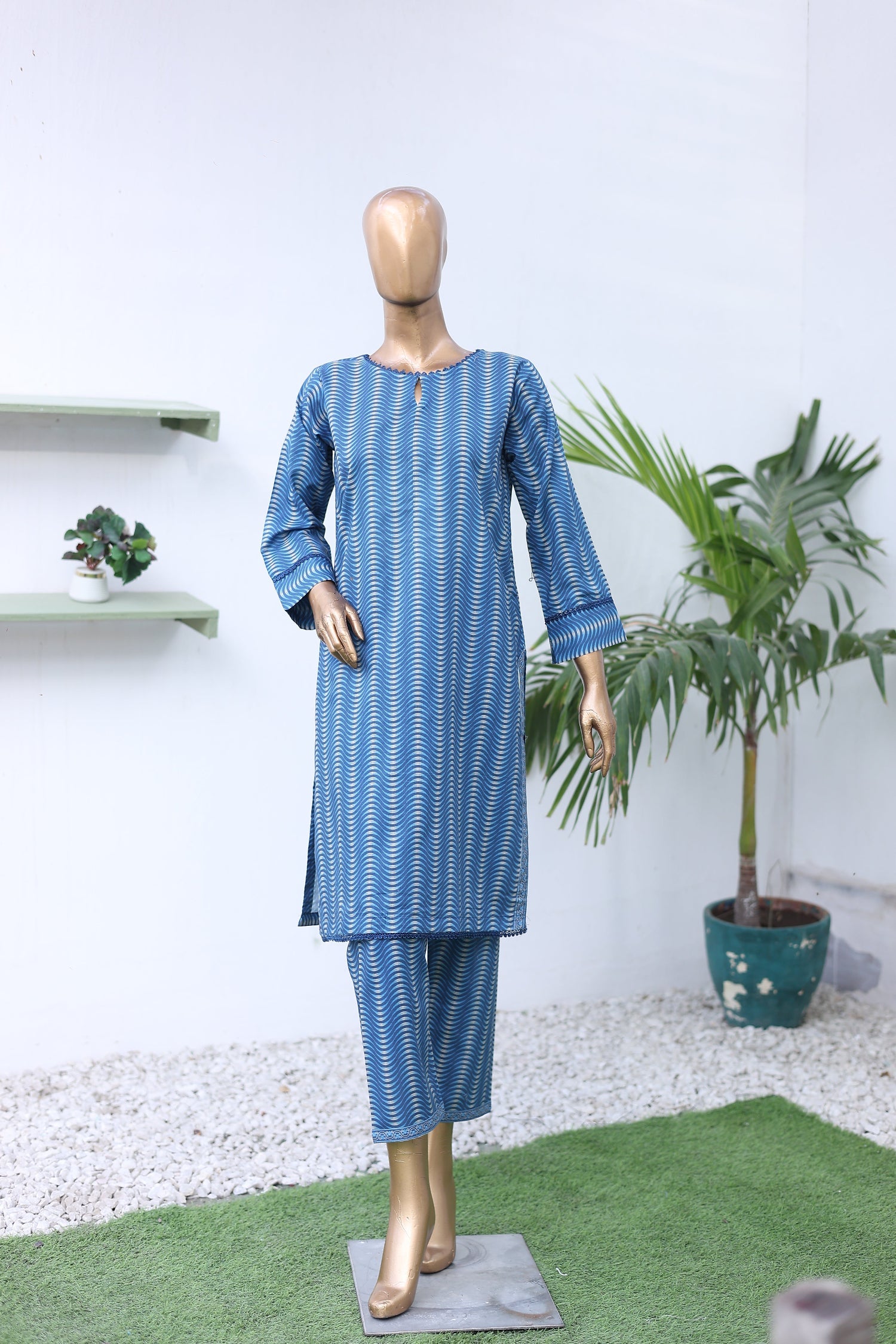 Mannequin wearing a blue and white striped outfit with a plant in the background