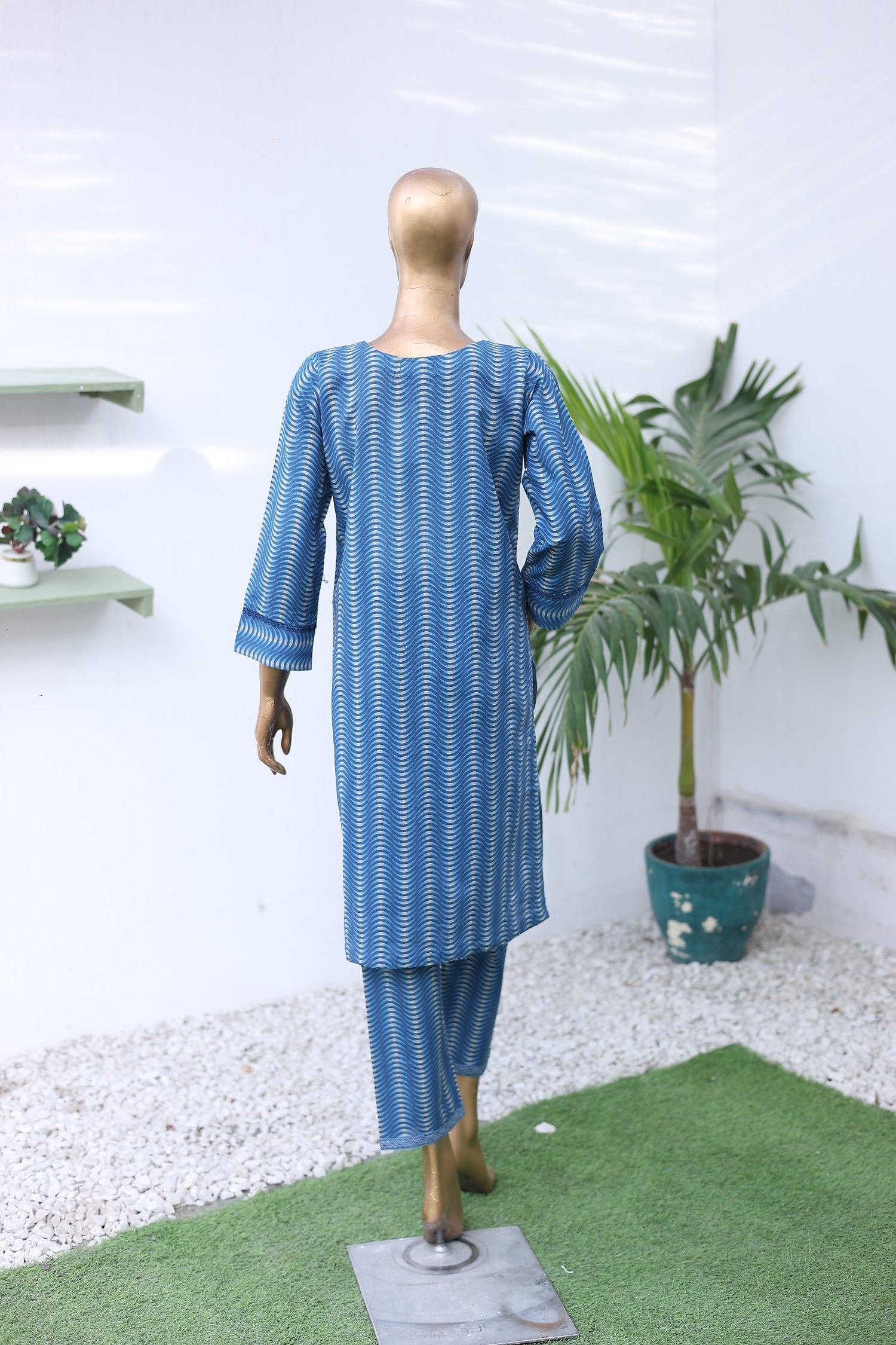 Mannequin wearing a blue and white striped outfit with a plant on a white background