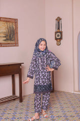 A girl wearing a long-sleeved embroidered shirt with laser lace cutwork, paired with a printed dupatta and trousers, standing in a room with a patterned floor.