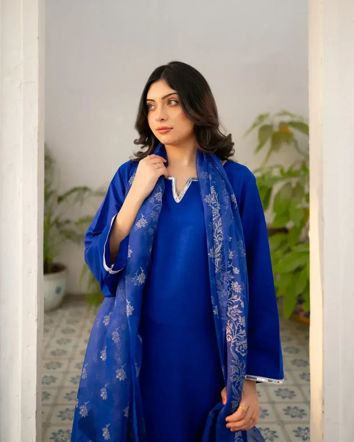 Woman wearing a royal blue traditional outfit with a matching dupatta indoors.