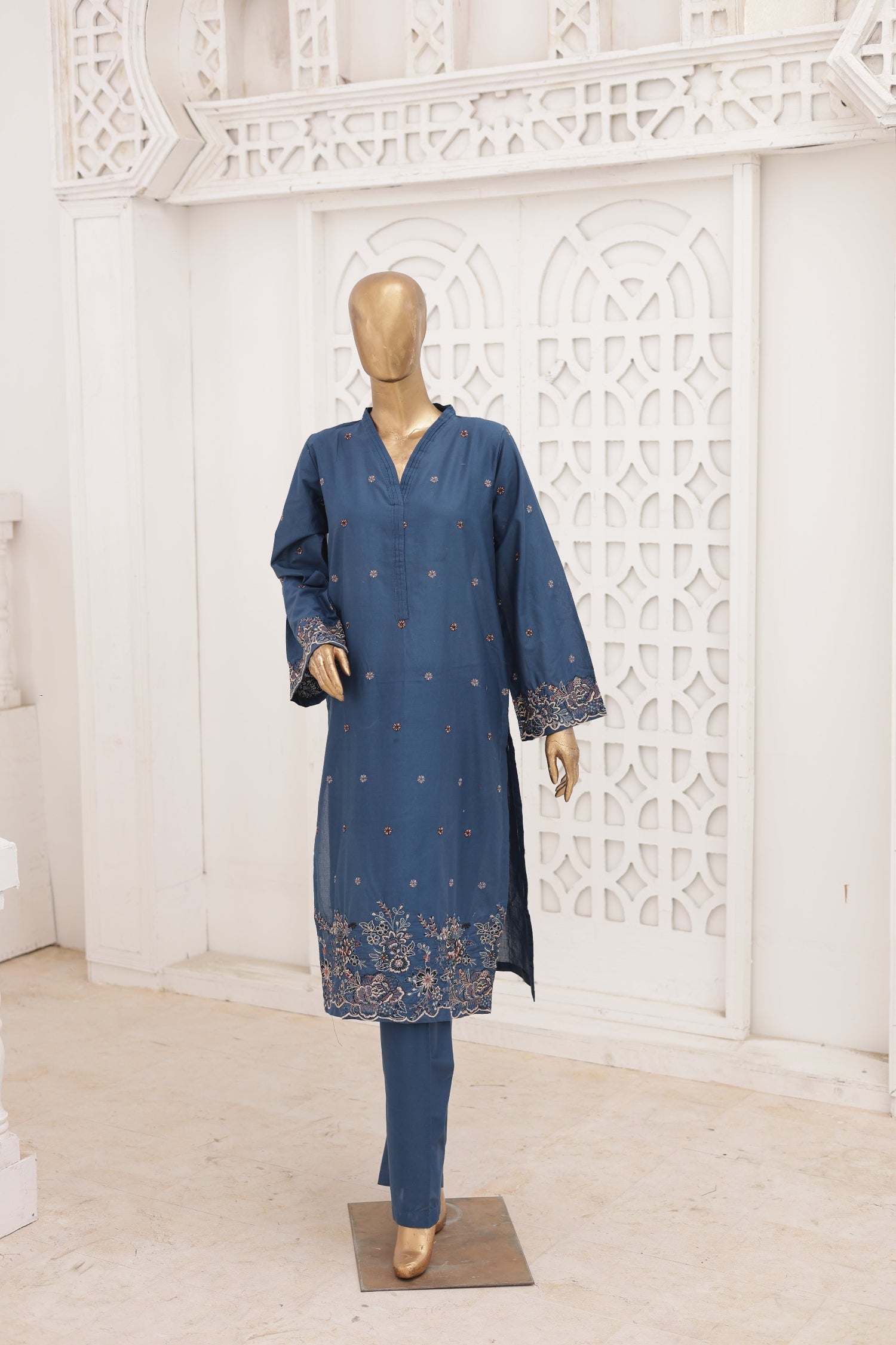 Mannequin wearing a blue embroidered kurta with pants against a white decorative wall.