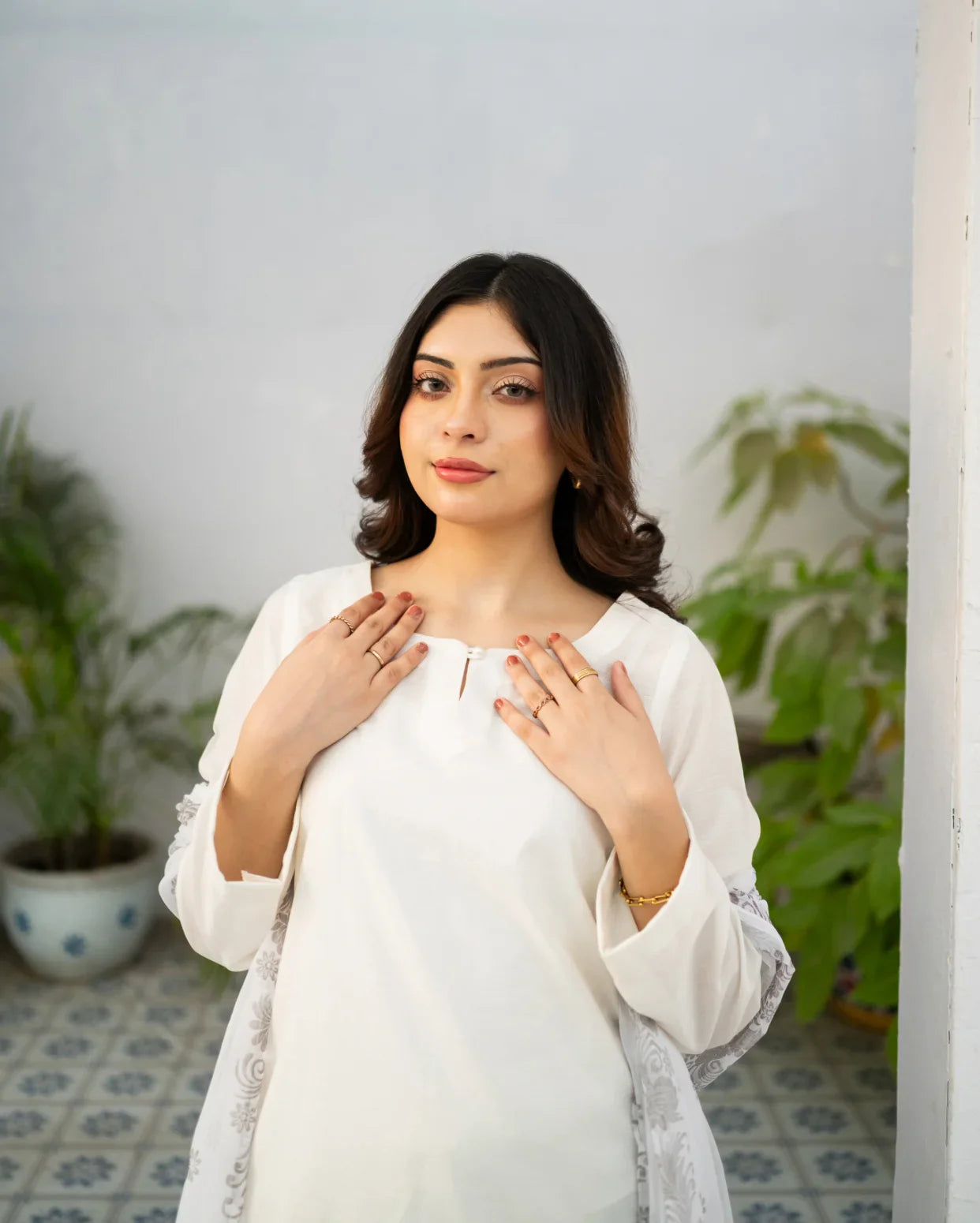 Woman wearing a white outfit with plants in the background